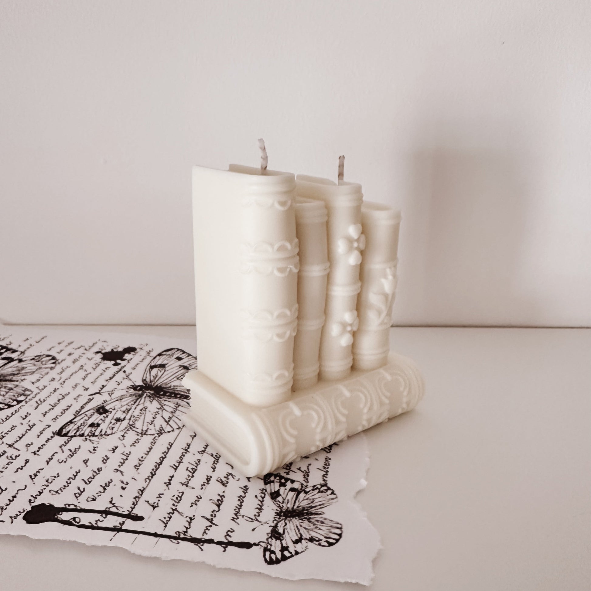 Vela artesanal em forma de pilha de livros em tons neutros para decoração slow living. Tsuki Studio.