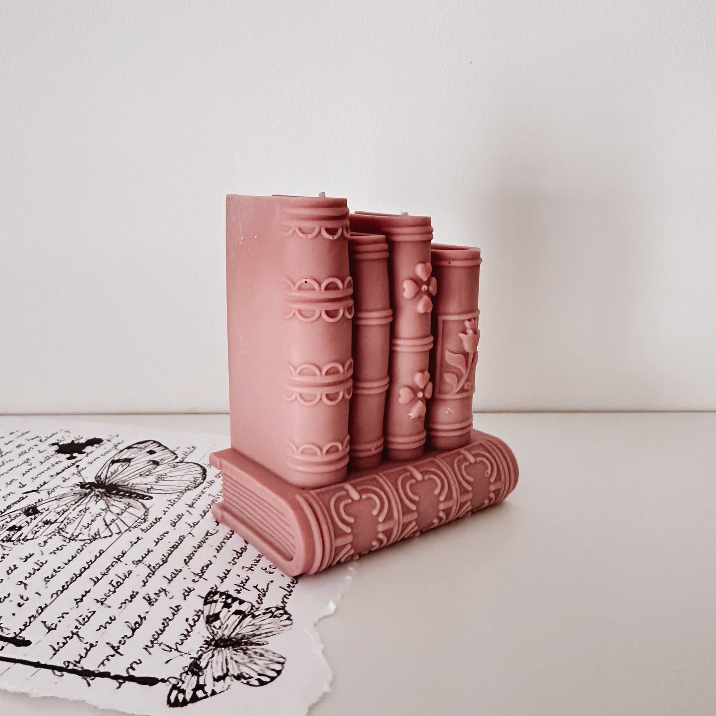 Vela decorativa artesanal em forma de pilha de livros rosa velho. Feita à mão em Portugal. Tsuki Studio.
